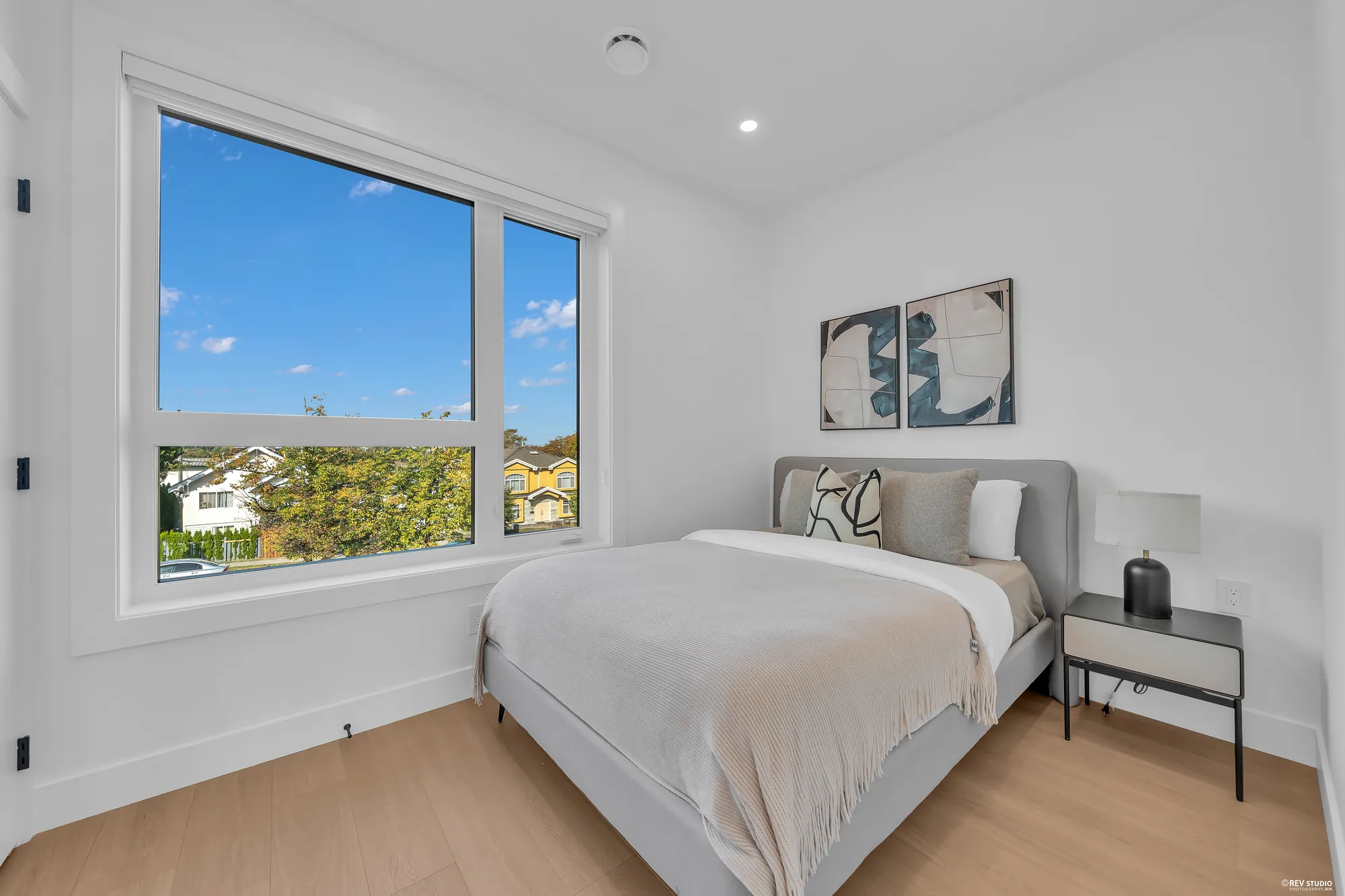 The front bedroom: a double bed under a framed print, the window to the street and the trees