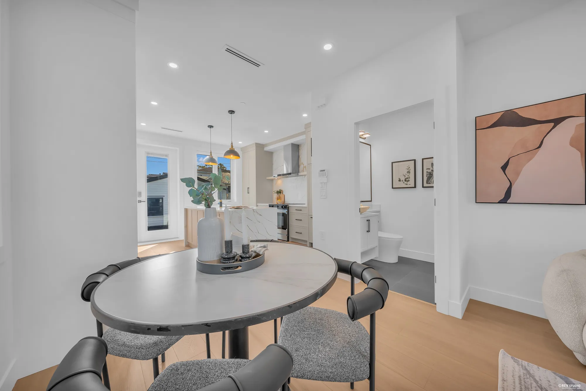 The dining area: a round table and chairs, the hall to the kitchen, the powder room door