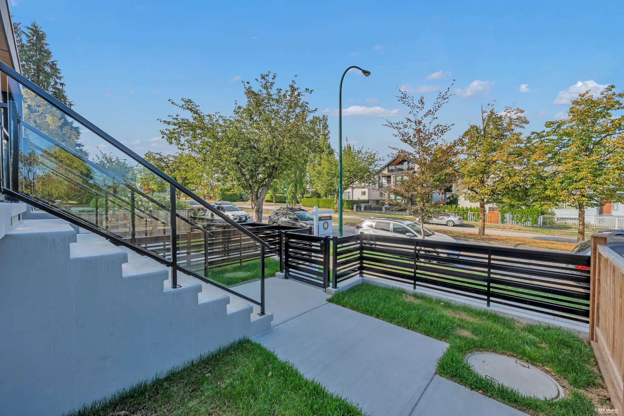 From the sidewalk: the stair up to the porch, the black railings, the street trees