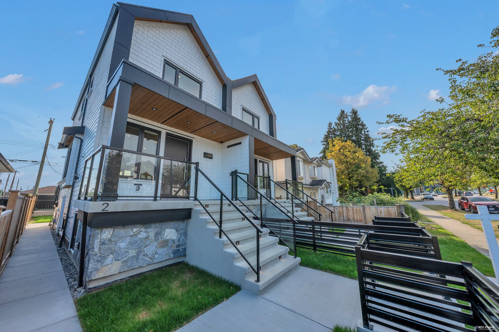 The house from the side: the porch, the stone base, the cedar fence along the property line