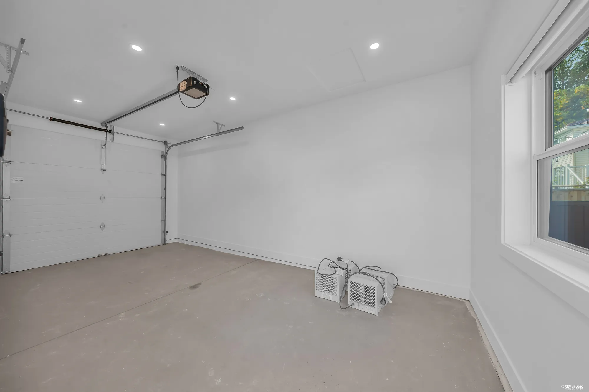 Inside the single garage: bare walls, the sectional door and its opener, a window