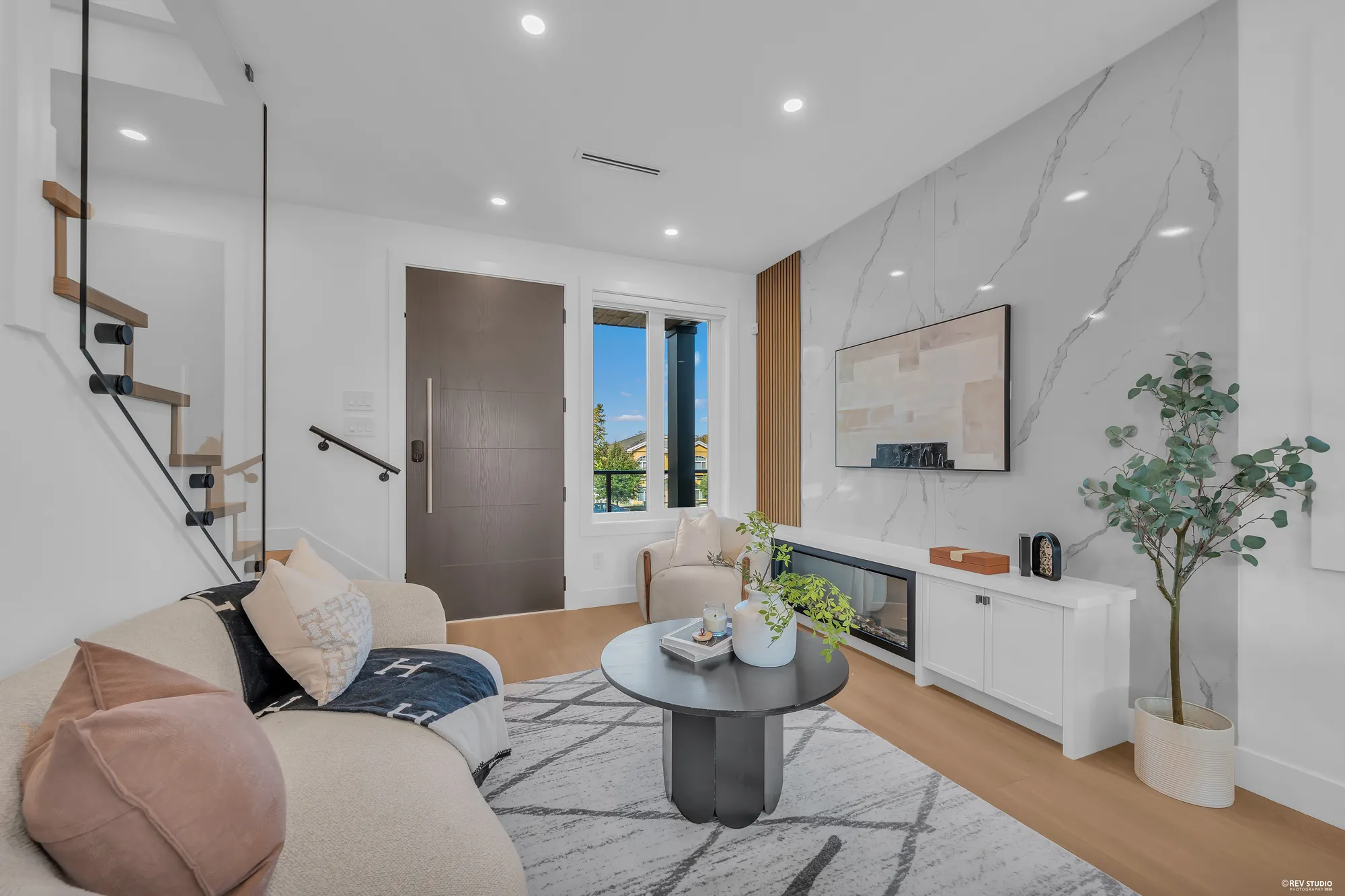 The living room toward the front door and the window, a curved sofa and a round table