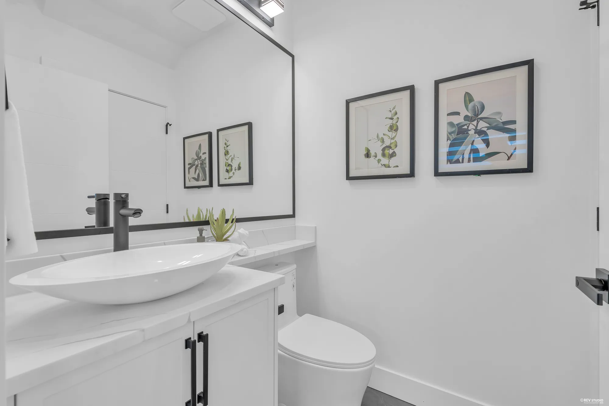 The powder room: a vessel sink on a white vanity, a black tap, two framed prints