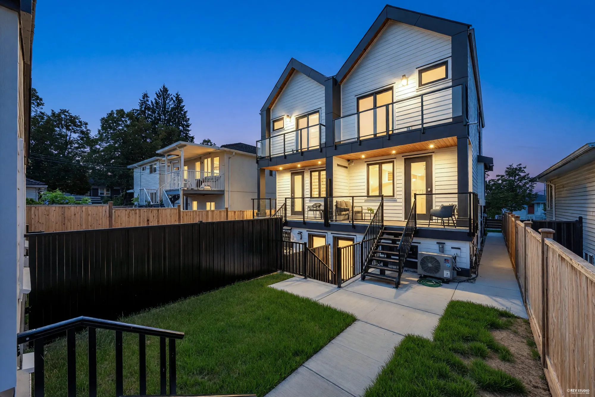 The same view of the back at dusk, the porch ceilings and the rooms behind them lit