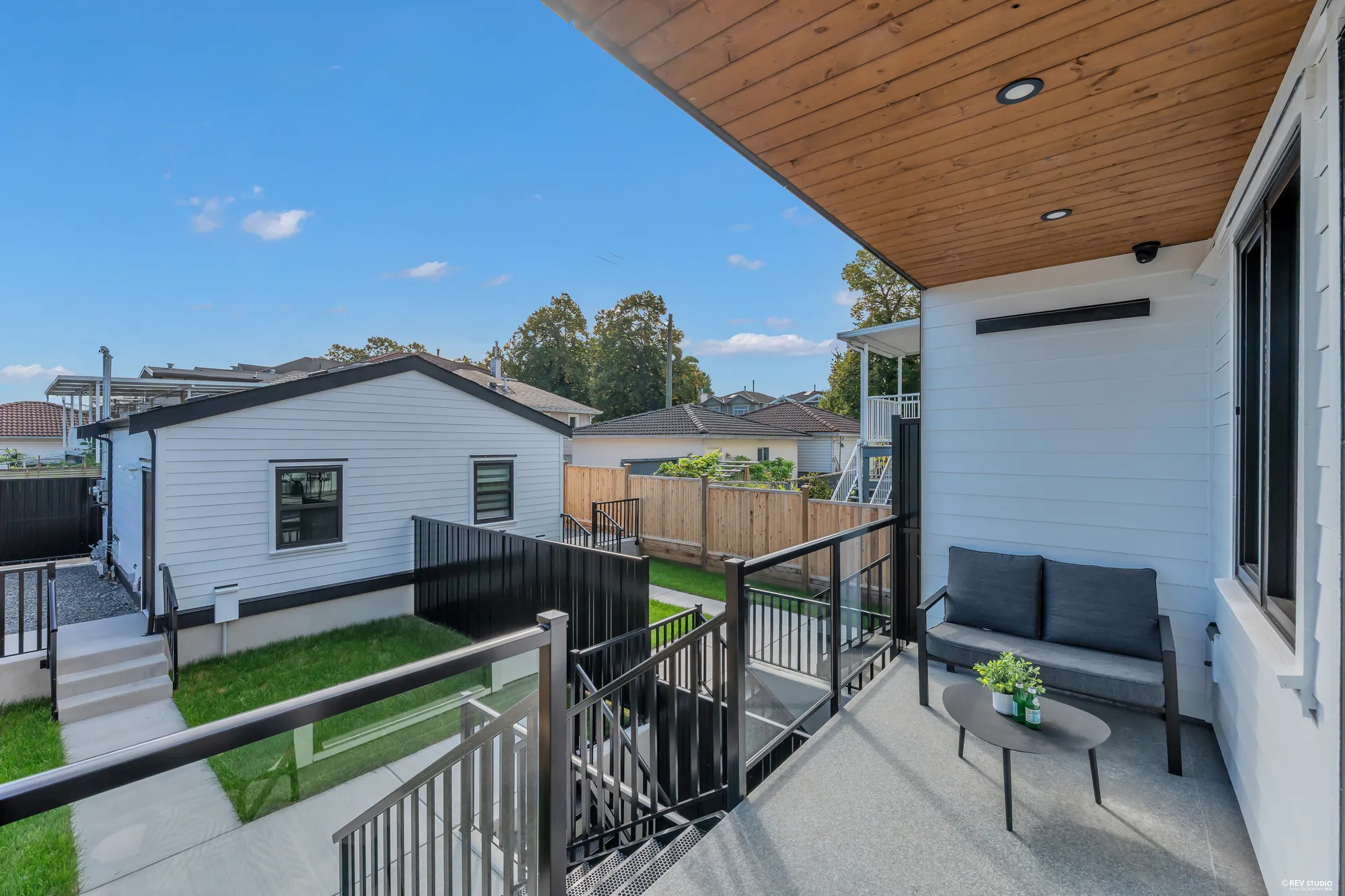 The covered back porch off the kitchen: a cedar ceiling, a bench, the yard and the garage below