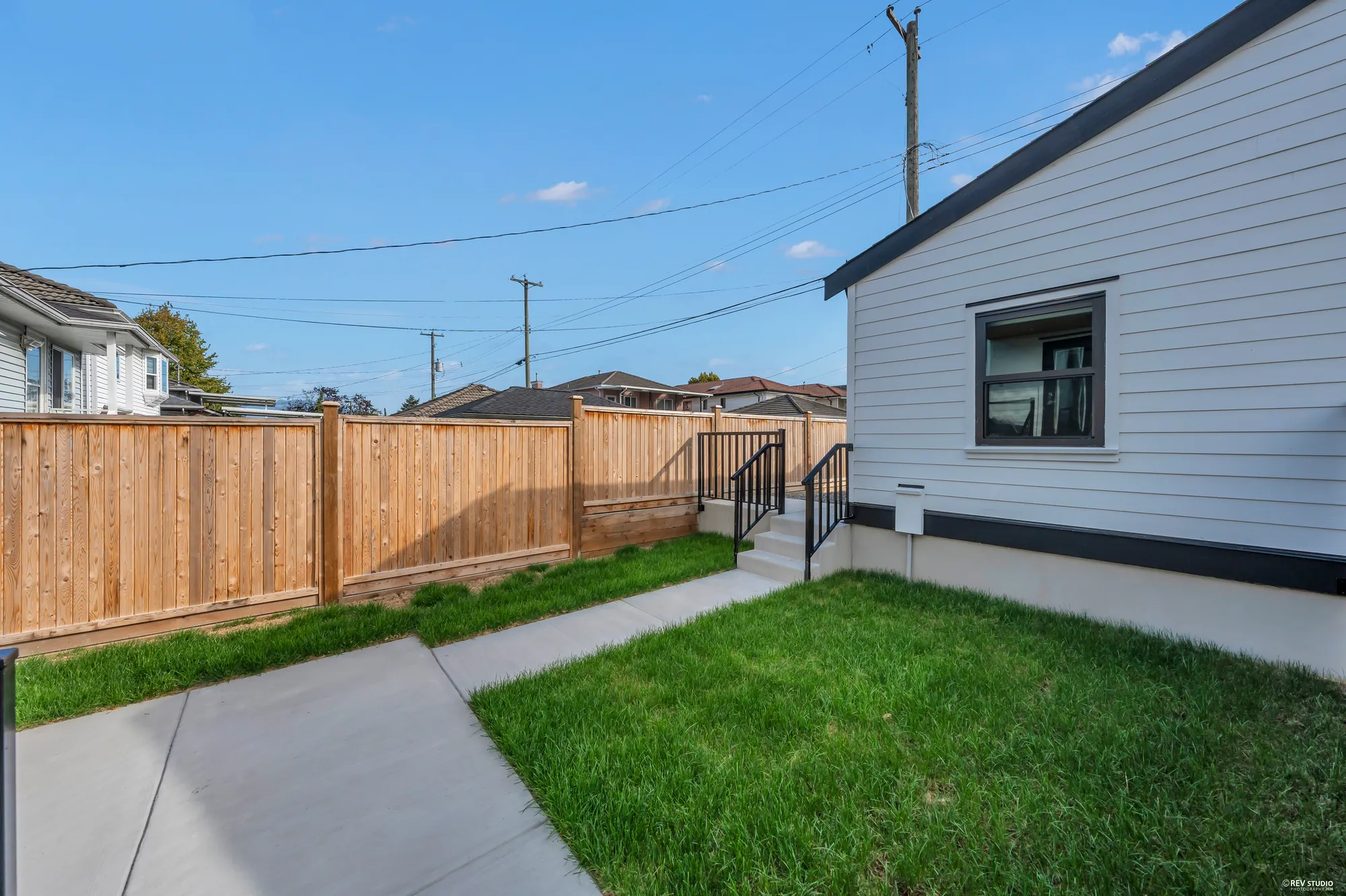 The garage and the cedar fence at the back of the yard, the turf in front